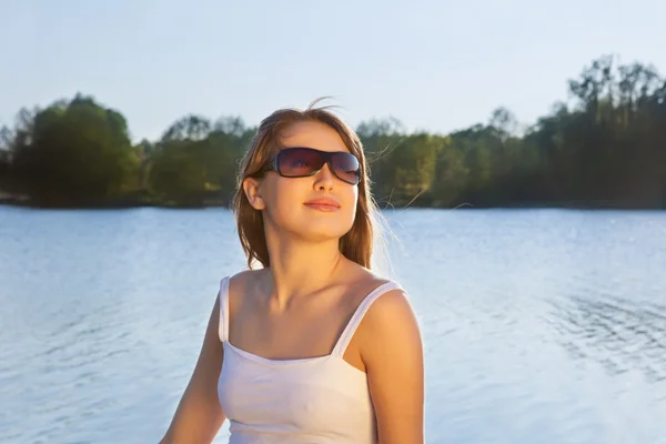 Junge Frau mit Sonnenbrille auf Wasserhintergrund — Stockfoto