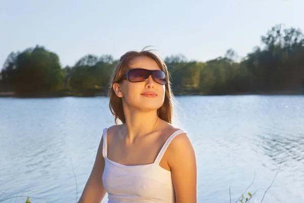 Giovane donna in occhiali da sole su sfondo acqua — Foto Stock