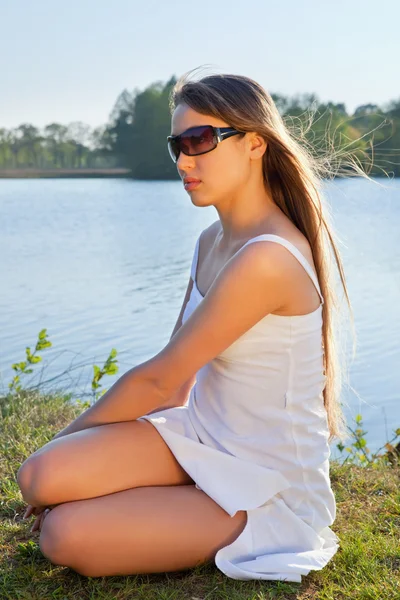 年轻女子在水背景上的太阳镜 — 图库照片