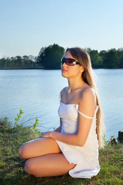 Mladá žena v sluneční brýle na pozadí vody — Stock fotografie