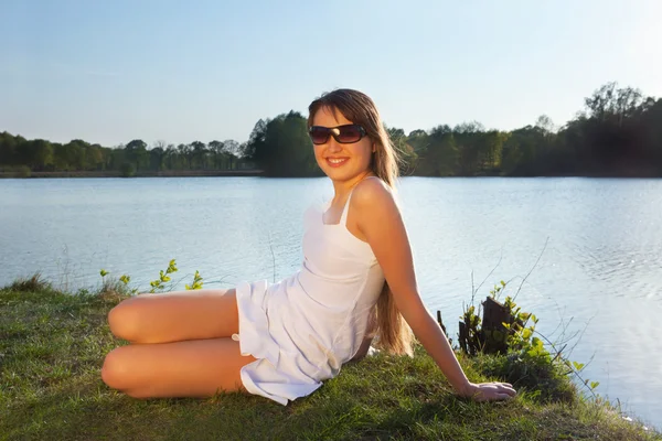 Genç kadın su arka plan üzerinde güneş gözlüğü — Stok fotoğraf