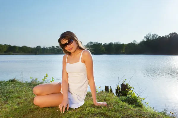 Jonge vrouw in zonnebril op water achtergrond — Stockfoto
