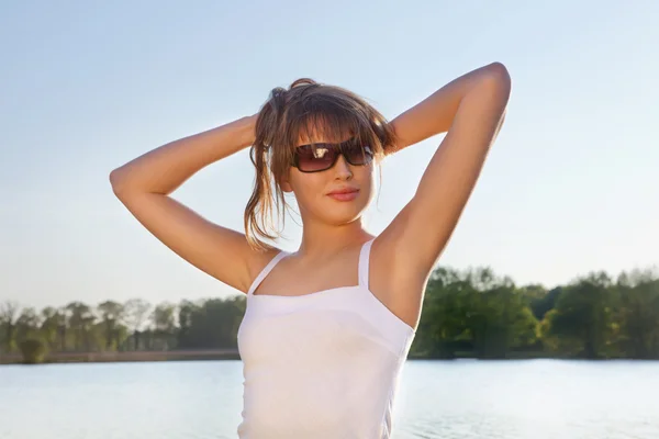 Junge Frau mit Sonnenbrille auf Wasserhintergrund — Stockfoto