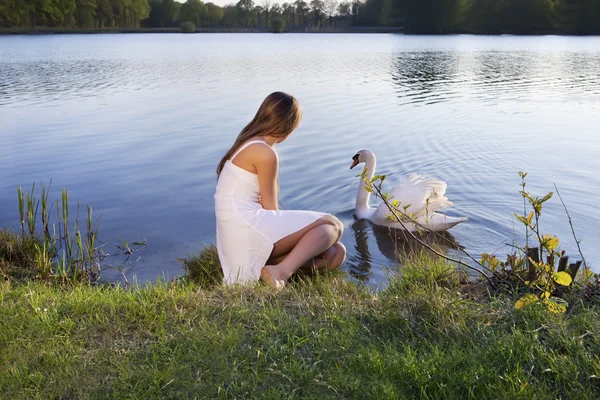 Blonde vrouw op water achtergrond en zwaan — Stockfoto