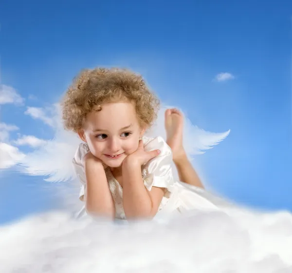 Kleines Mädchen mit Feenflügeln liegt auf einer Wolke — Stockfoto