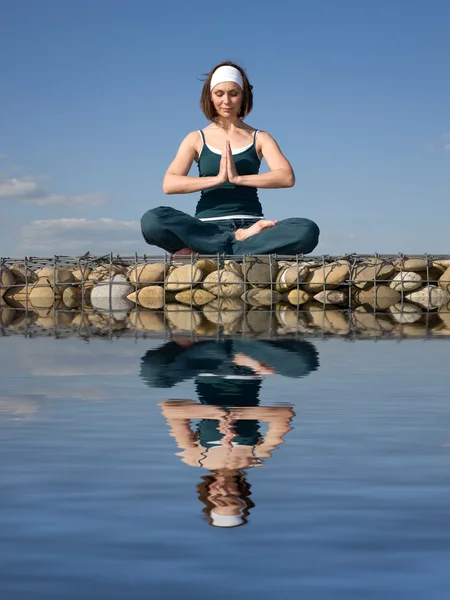Bir kadın bir suyun üzerinde yoga yaparken — Stok fotoğraf