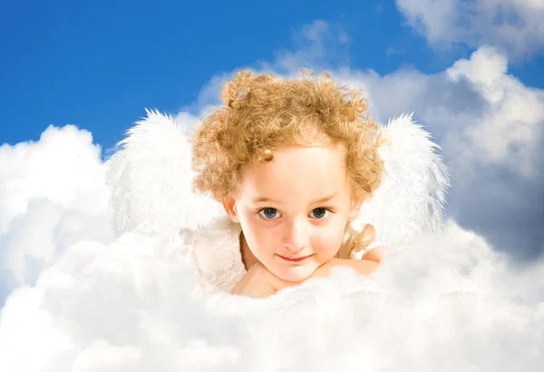 Маленька дівчинка з казковими крилами лежить на хмарі — стокове фото