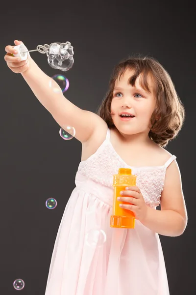 Маленька дівчинка дме мильні бульбашки — стокове фото