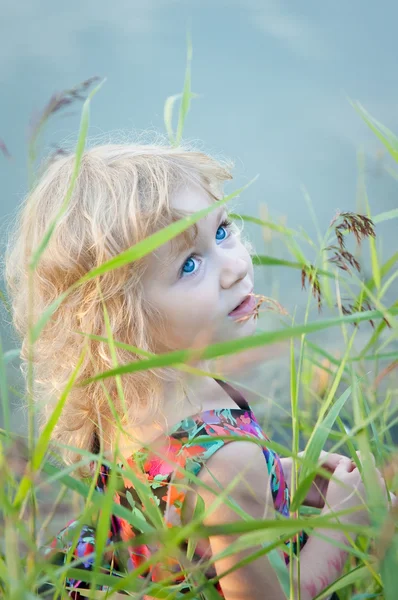 Маленька дівчинка сидить наодинці на березі річки — стокове фото