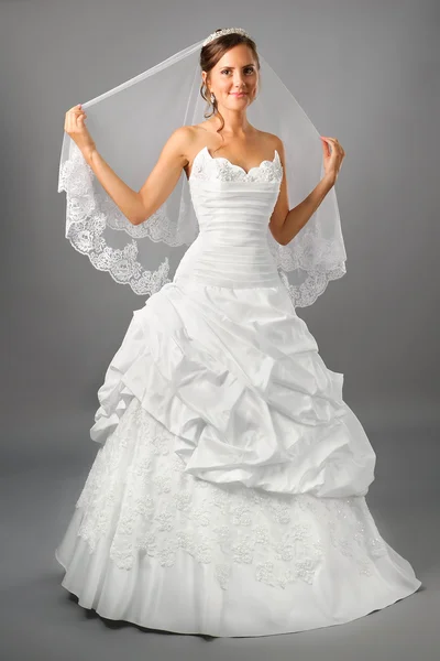 Schöne Braut unter Schleier Kleid auf dem neutralen Hintergrund — Stockfoto