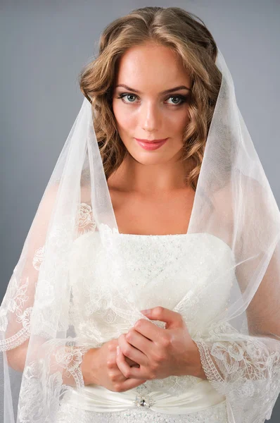 Krásná nevěsta pod závojem na studio neutrální pozadí — Stock fotografie