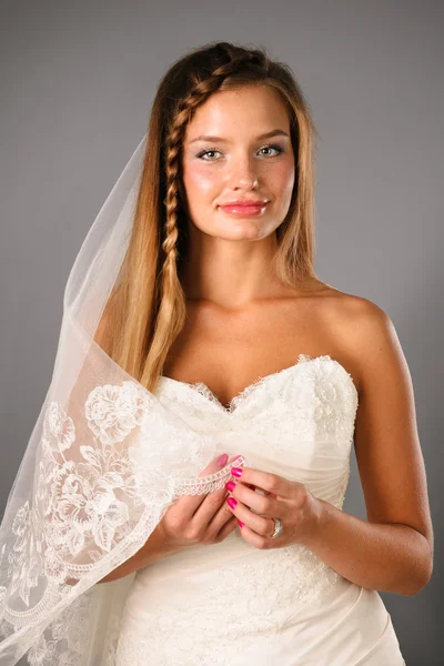 Béatifique jeune mariée portant une robe de mariée sur fond neutre studio — Photo