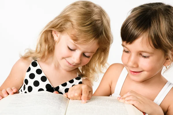 Дві дівчини дошкільного віку, що червоніють книгу, ізольовані на білому — стокове фото