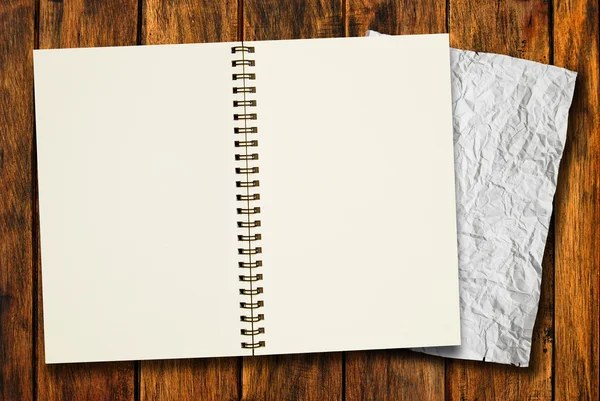 Caderno em branco com papel amassado sobre fundo de madeira — Fotografia de Stock
