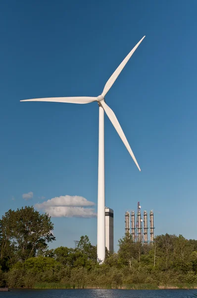 Большая ветряная турбина с деревьями и голубым небом — стоковое фото