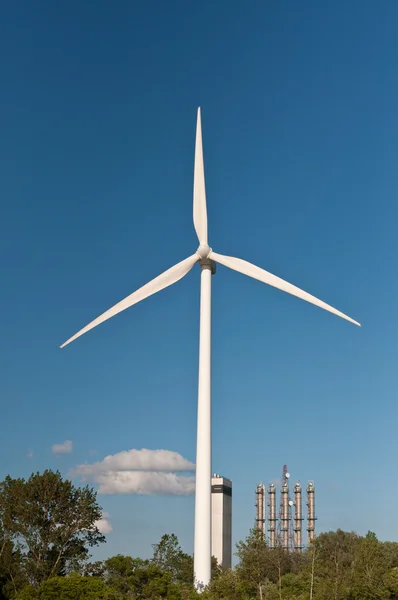 Большая ветряная турбина с деревьями и голубым небом — стоковое фото