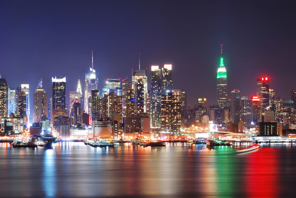 Urban city night scene. Empire State Building, New York City with Manhattan Skyline at night panorama over Hudson River with reflection.