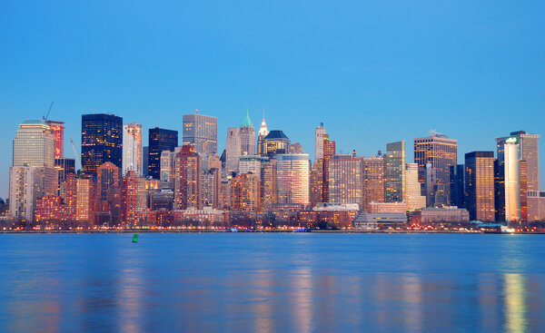 Manhattan Skyline at dusk, New York City, with lights in offices buildings over Hudson River.