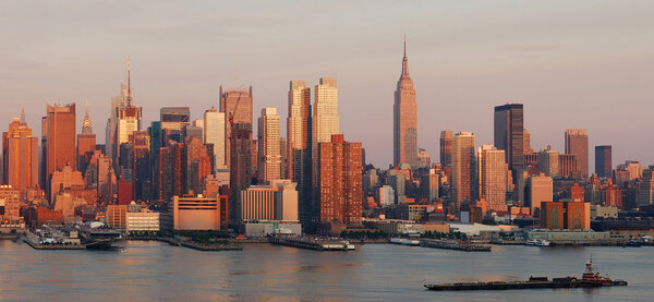 New York City Manhattan skyline panorama at sunset with empire state building and skyscrapers with reflection over Hudson river.