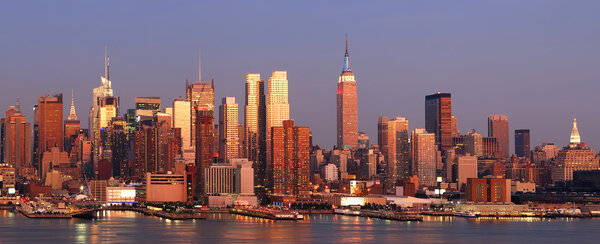 New York City Manhattan skyline panorama at sunset with empire state building, Times Square and skyscrapers with reflection over Hudson river.