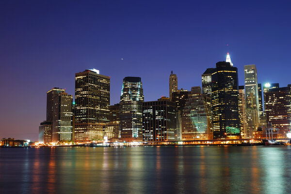 New York City Manhattan urban skyline over Hudson River with office skyscrapers building in at dusk illuminated with lights at night