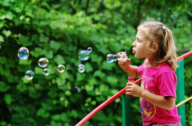 Little girl making soap bubbles clipart