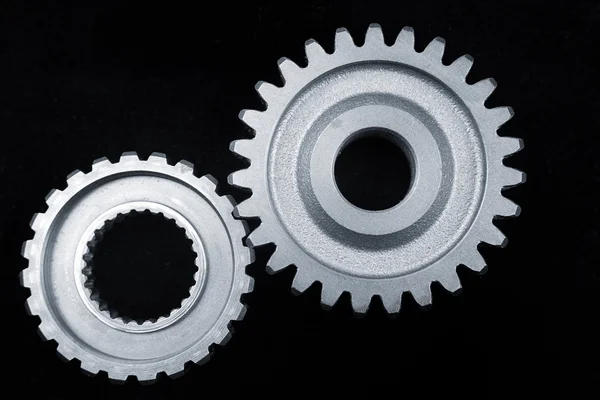 Two gears meshing together on black surface — Stock Photo, Image