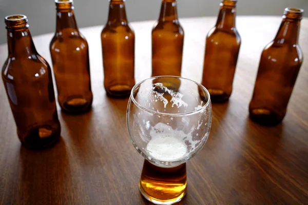 Glass of beer and bottles on table — Stock Photo, Image