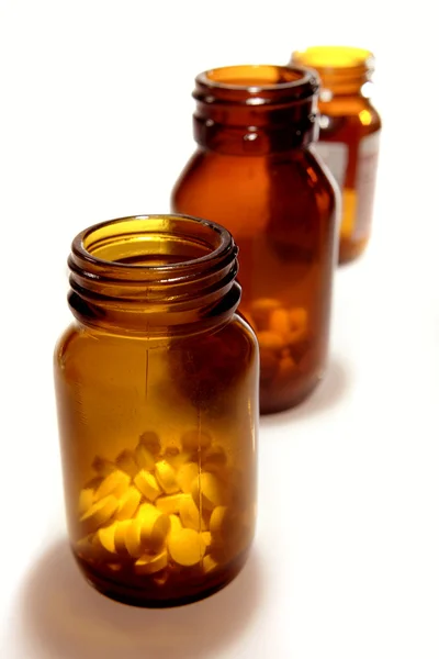 Tres botellas de pastillas sobre fondo liso —  Fotos de Stock