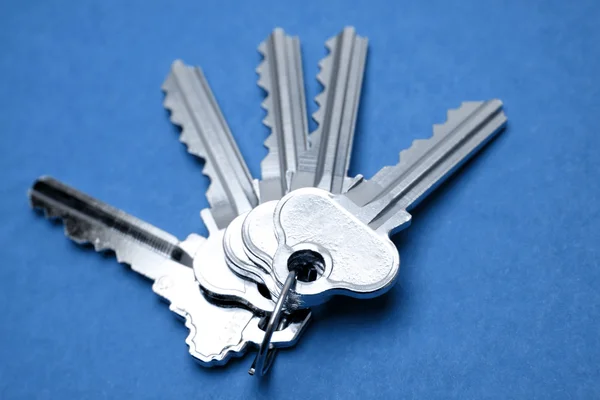 Five door keys on blue background — Stock Photo, Image