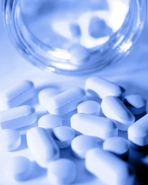 Piller som rinner från burk, blå ton — Stockfoto