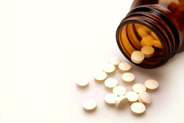 Piller som rinner från flaska till enfärgad bakgrund — Stockfoto