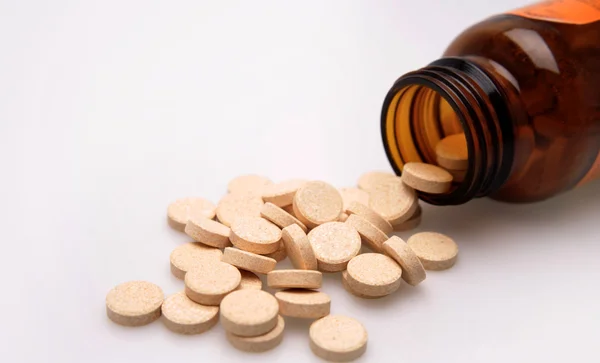 Pílulas de vitamina derramando de garrafa de vidro — Fotografia de Stock