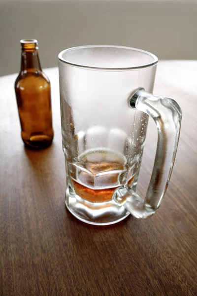 啤酒瓶和桌上的空杯 — 图库照片
