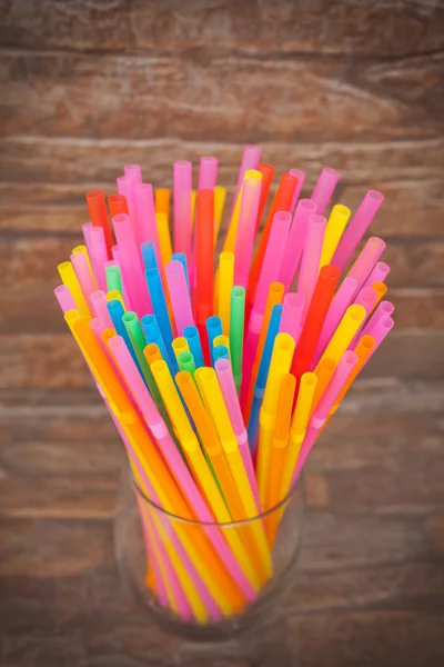 Colorful plastic straws in glass on brick background — Stock Photo, Image