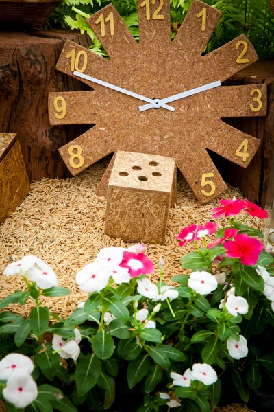 Часы из дерева в цветочном саду — стоковое фото