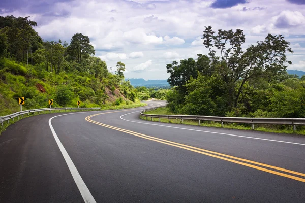 Asphalt road along with tropical forest zigzag ahead. — Stock Photo, Image