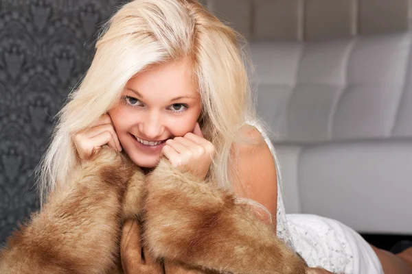 Glimlachend blond meisje houden een bontjas — Stockfoto