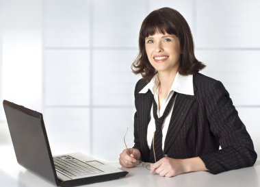 Business woman spectacled works with a laptop clipart