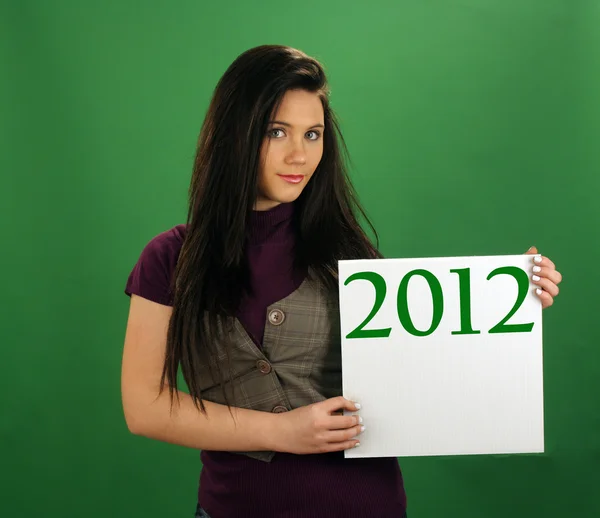 Hermosa chica adolescente sostiene una tarjeta blanca con "2012" en ella —  Fotos de Stock