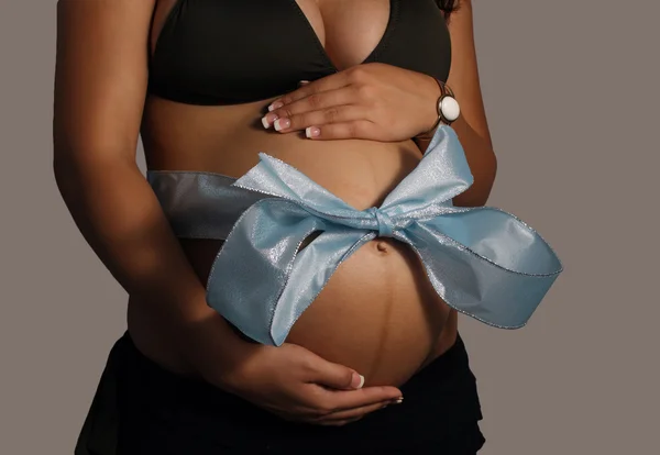 Ventre féminin enceinte avec arc bleu — Photo