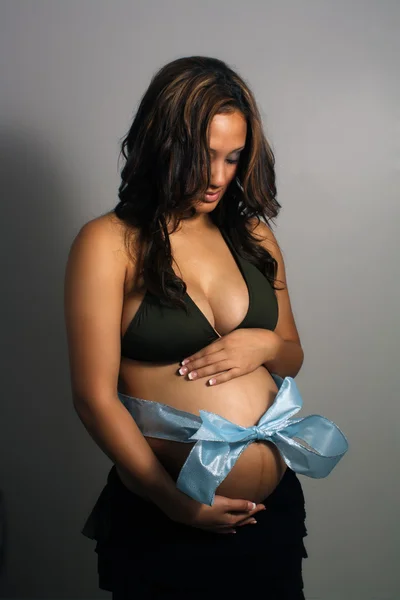 Mulher grávida com arco azul em torno de sua barriga — Fotografia de Stock