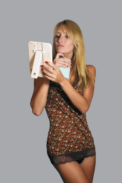 Schöne Blondine mit einer Flasche Lotion und einem Handspiegel (2) — Stockfoto