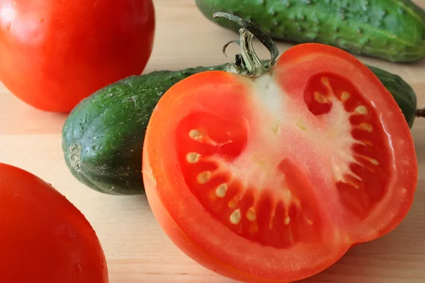 Pöydällä puolet tomaattia ja kurkkua — kuvapankkivalokuva