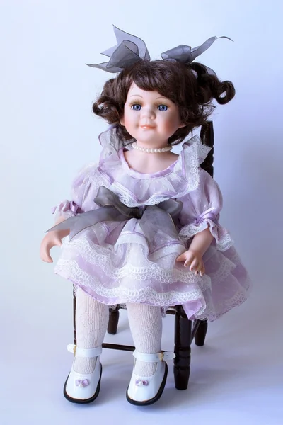 Ručně vyráběné porcelánová panenka sedí na židli — Stock fotografie