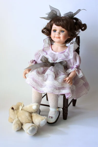 Urso de pelúcia e uma boneca em uma cadeira em um fundo leve — Fotografia de Stock