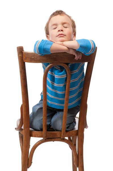 Kleine jongen zit in stoel met zijn ogen dicht — Stockfoto