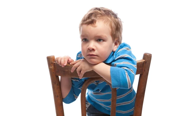 Smutny chłopiec siedzi na krześle — Zdjęcie stockowe