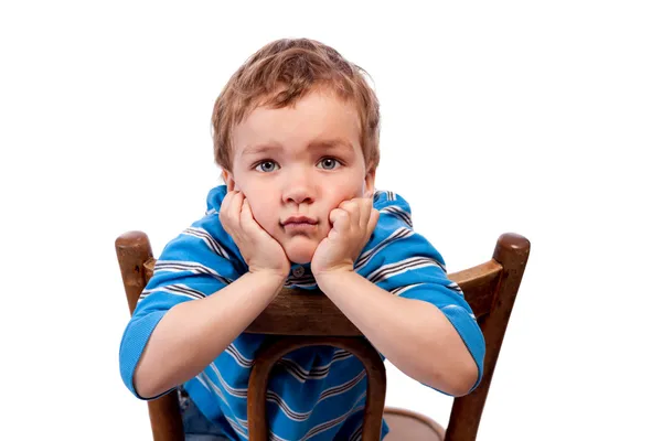 Сумний хлопчик сидить на стільці — стокове фото