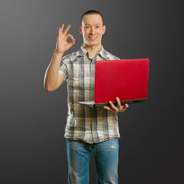Asijské muž s notebookem v jeho rukou ukazuje ok — Stock fotografie